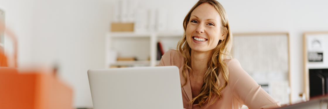 30 best promo video ideas for your business, product, or event Smiling woman using Biteable video maker on a laptop in a bright office setting.