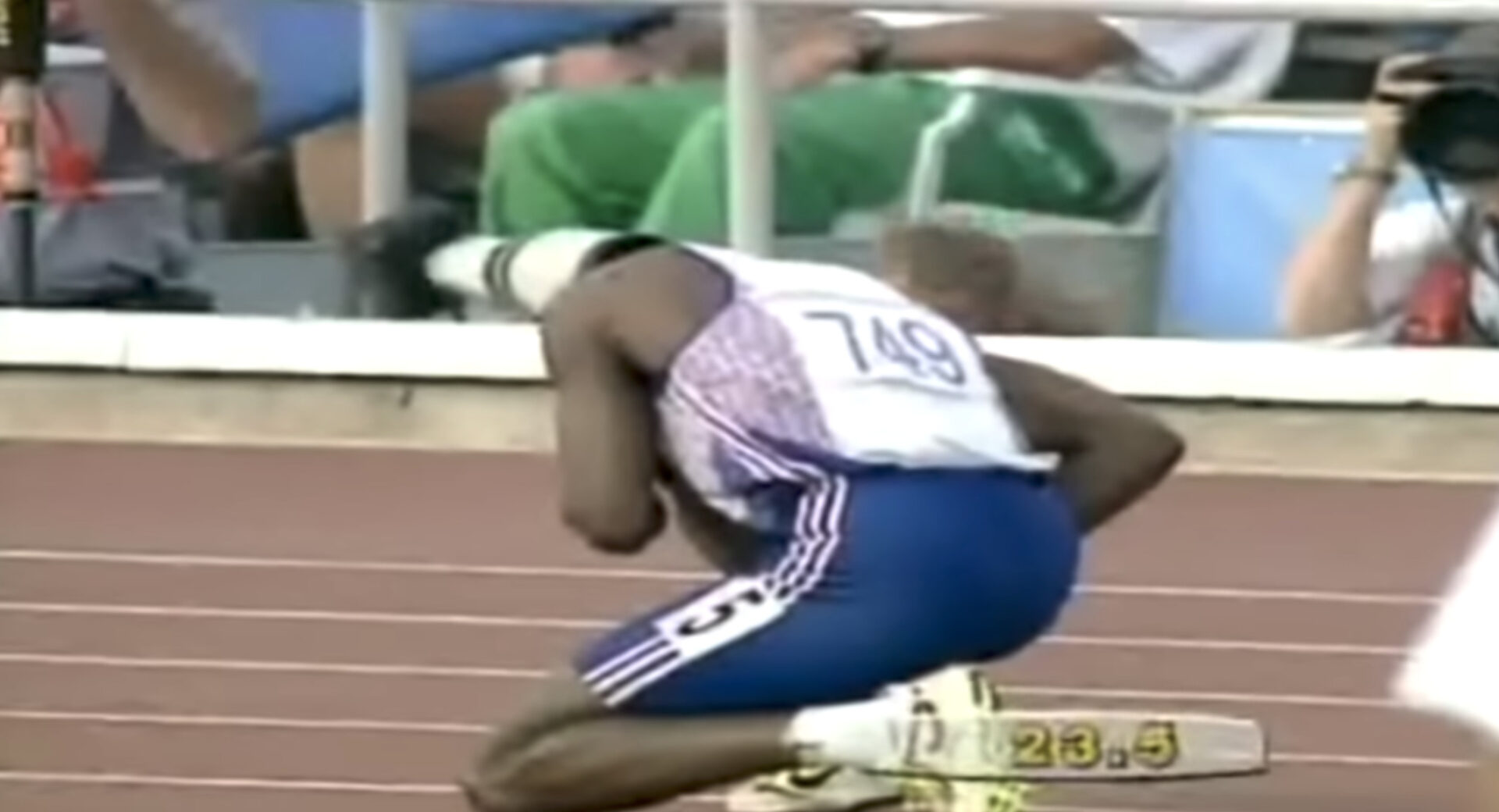 A male athlete, numbered 749, in a crouched starting position on a track, wearing a white and blue uniform designed for a Biteable video maker.