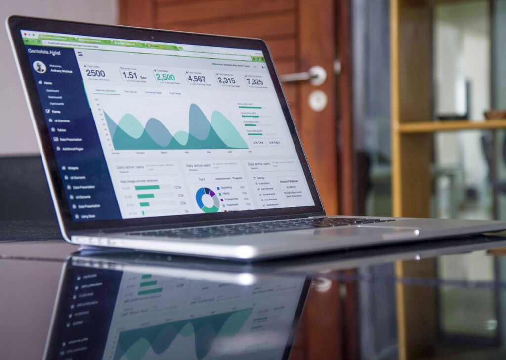 Laptop with analytics dashboard displayed on the screen, placed on a glass table in an office environment.