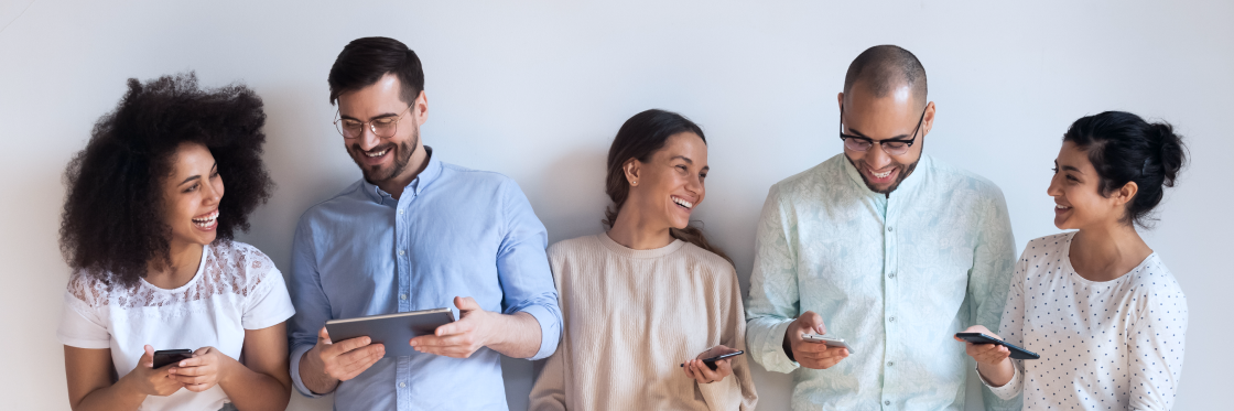 The 7 different types of social media Group of five diverse friends smiling and looking at their phones and a tablet, exploring different types of social media.