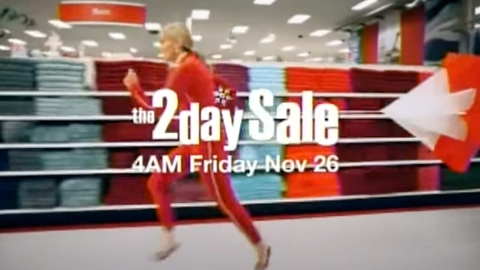 A woman in a red suit runs past shelves of merchandise in a store advertising a '2 day sale' event, captured elegantly by Biteable video maker.