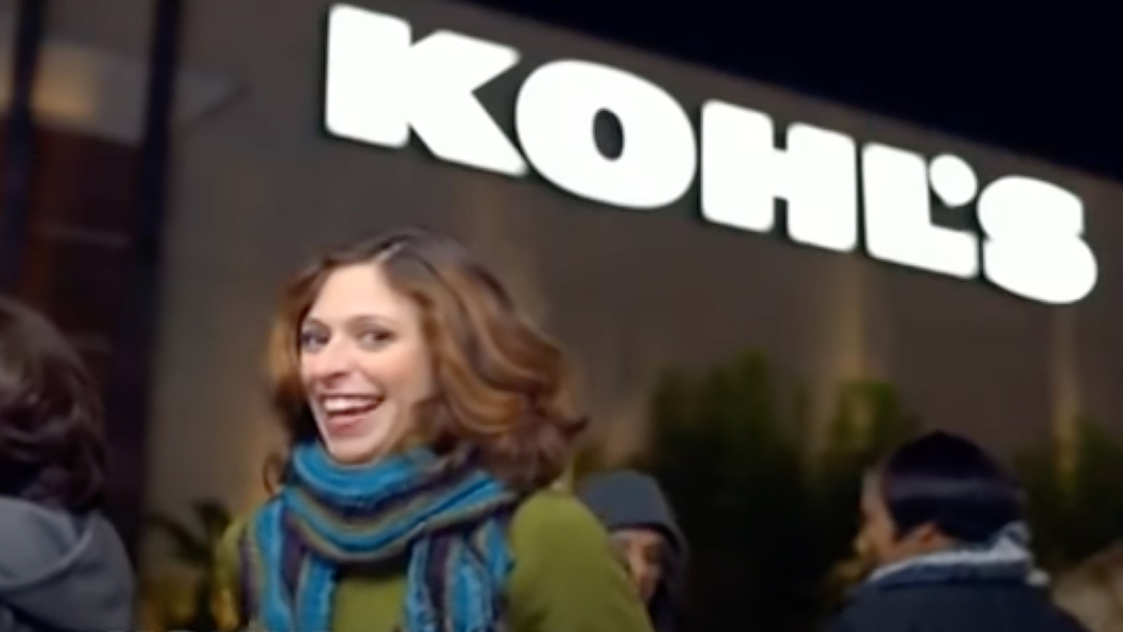 A woman smiling broadly in front of a Kohl's store sign during nighttime, captured perfectly in a Biteable video.
