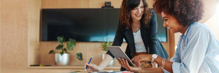 Two professionals collaborating with a digital tablet in a modern office setting.