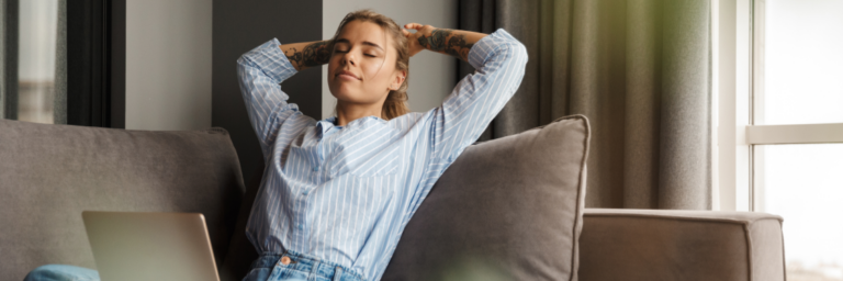Woman relaxing on a couch with a laptop nearby.