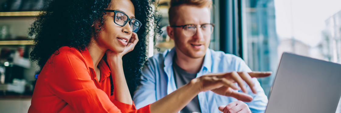 YouTube analytics 10 metrics you really should be measuring Two professionals discussing work on a laptop in a modern office setting.