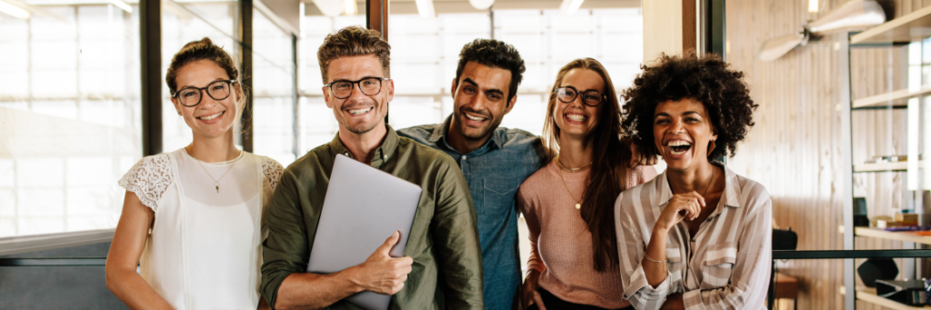 A group of five cheerful colleagues posing together in an office environment for a Biteable video.