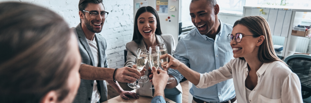 Group of colleagues celebrating with a champagne toast in an office environment.