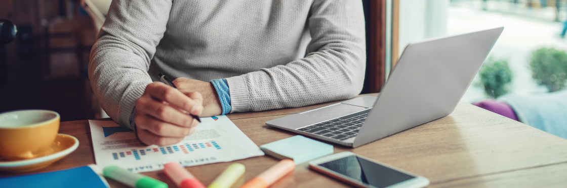 How MediCompare increased conversions and lowered their bounce rate with one video Person working on finances with laptop and documents at a coffee shop.