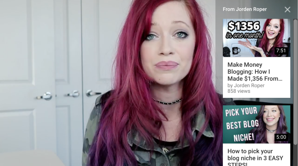 Woman with pink hair presenting a video about making money from blogging.