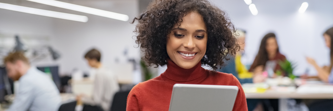 Video for internal comms Woman smiling at tablet screen in a modern office environment.