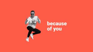 Man in sunglasses and a t-shirt, jumping joyfully with thumbs up, against a bright orange background with text "because of you", created using Biteable video maker.