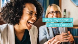 A woman with curly hair laughs joyfully in a meeting as another participant gestures while speaking, captured in a Biteable video, with a name tag "Lauren Cundall" visible.