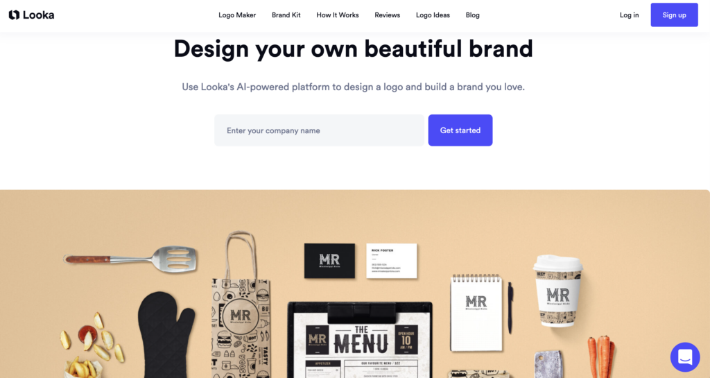 Webpage screenshot of Biteable video maker homepage featuring a text box to enter a company name, surrounded by various branded items like menus and cups on a beige background.