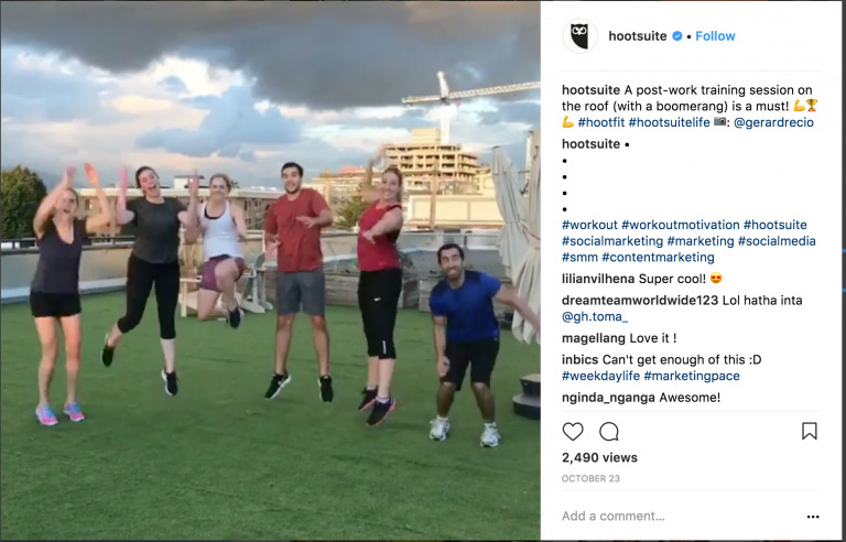 A group of people joyfully jumping in unison during an outdoor workout on a rooftop, captured with Biteable video maker, with the city skyline visible in the background.
