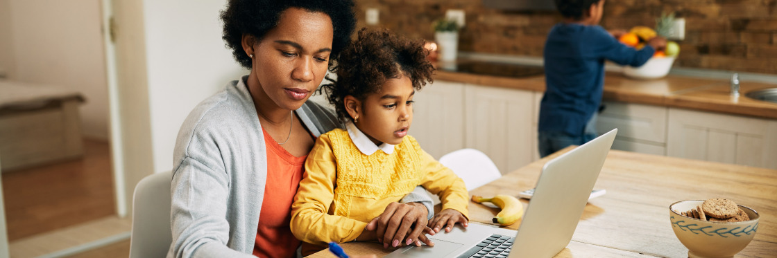 Work from home statistics A mother and her young daughter sit at a kitchen table, using a Biteable video maker on a laptop together, while a boy plays in the background.