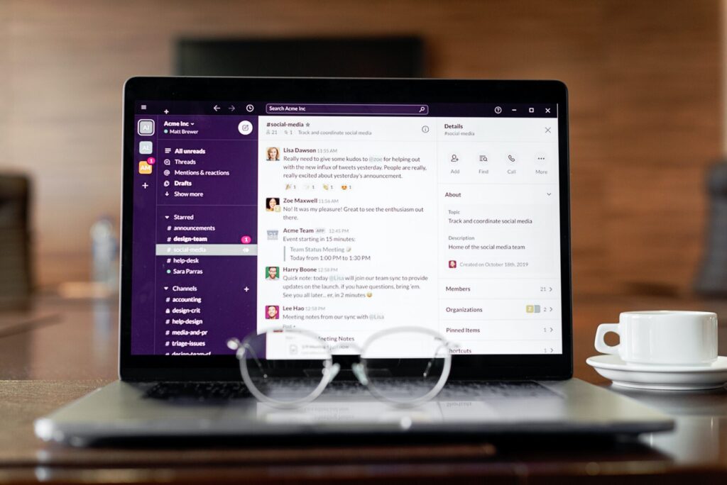A tablet displaying a social media application on screen, rested on a wooden table with a pair of glasses in front and a coffee cup to the side.