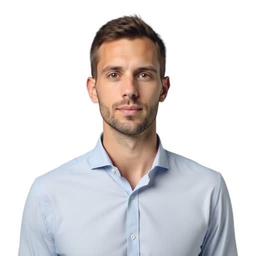 A man with short brown hair and light stubble, wearing a light blue button-up shirt, stands against a plain white background.