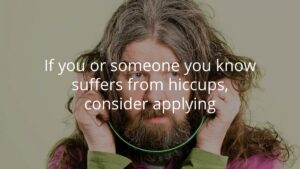 A person with long hair and a beard holds a stethoscope to their head. Overlaid text reads: "If you or someone you know suffers from hiccups, consider applying.